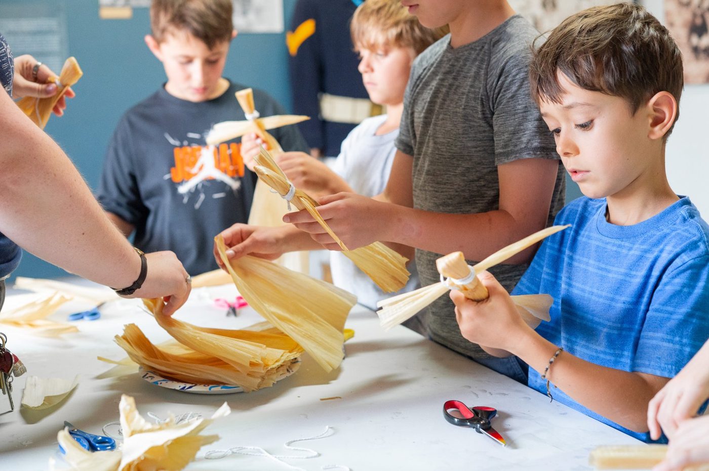 Campers making tamale-husk crafts